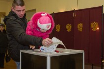 Мужчина с ребенком опускают бюллетень в урну для голосования на избирательном участке №1659 в Нижегородском  районе города в день выборов депутатов Государственной Думы РФ шестого созыва