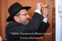 Главный раввин России Берл Лазар исполняет заповедь - устанавливает у главного входа в синагогу мезузу – коробочку с текстом главной молитвы из книги Тора внутри